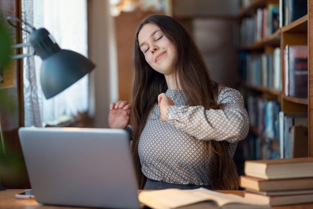 Felice studentessa ha attività di esercizio fisico mentre lavora al computer La giovane ragazza si prende cura della sua salute e fa esercizi periodicamente mentre lavora