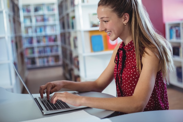 Felice studentessa utilizzando laptop in libreria