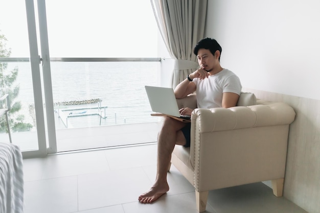 Felice sul divano con vista mare e concetto di lavoro staycation