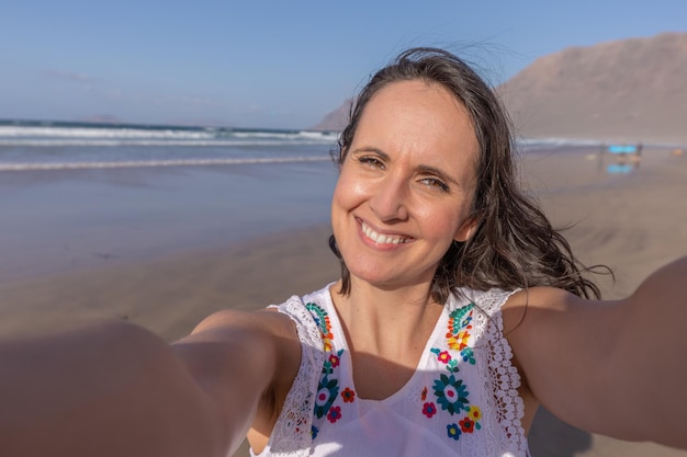 Felice turista femminile prendendo selfie vicino al mare