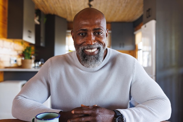 Felice uomo afroamericano che fa una videochiamata sorridendo alla telecamera in una baita. Natura, tempo libero, comunicazione e concetto di vacanza.