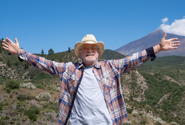 Felice uomo anziano con le braccia tese godendo della natura in montagna Paesaggio rurale e vulcano El Teide sullo sfondo Concetto di libertà