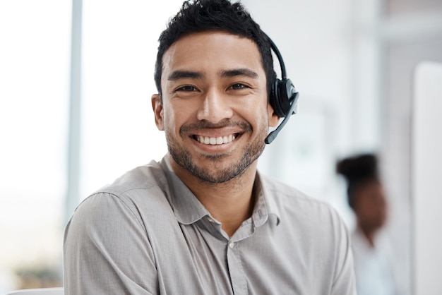 Felice uomo asiatico call center e ritratto sorriso con le cuffie nel servizio clienti o telemarketing in ufficio Volto dell'agente consulente uomo d'affari sorridente in consulenza online o televendite sul posto di lavoro