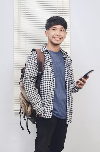 Felice uomo asiatico che indossa abiti casual tenendo il cellulare
