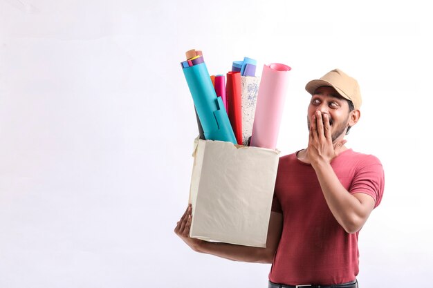 Felice uomo asiatico in t-shirt e berretto con scatola di carta colorata isolata su sfondo bianco, concetto di servizio di consegna
