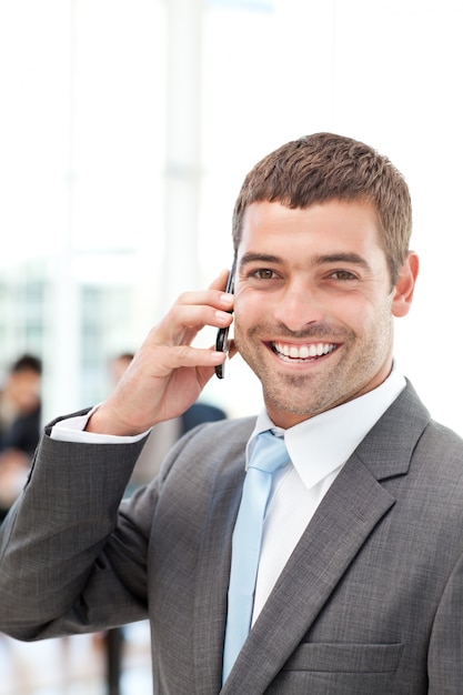 Felice uomo d&#39;affari ispanico al telefono mentre la sua squadra sta lavorando