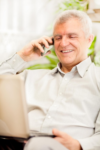 Felice uomo d'affari senior che lavora a casa sul computer portatile