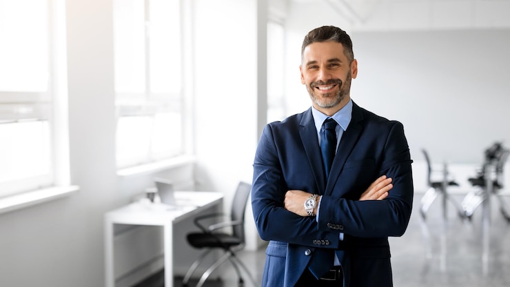 Foto felice uomo di mezza età manager in posa con le braccia incrociate in ufficio e sorridente alla copia panoramica della fotocamera