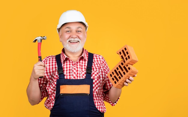 Felice uomo maturo lavoratore in casco su sfondo giallo