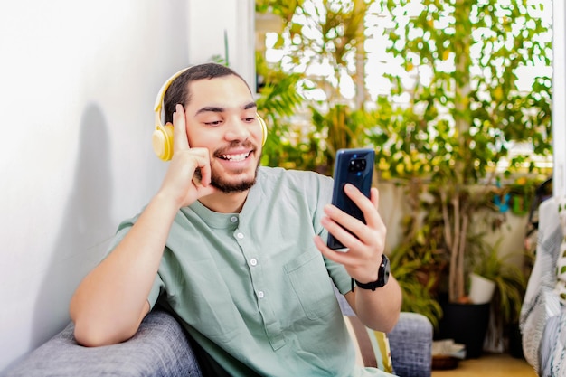 Felice uomo rilassato a casa utilizzando il telefono seduto sul divano