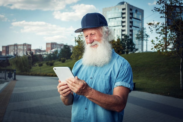 Felice vecchiaia. Il vecchio dai capelli grigi il pensionato usa un tablet con un sorriso.