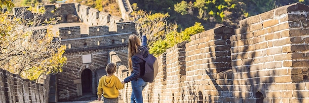 Felici allegri turisti gioiosi mamma e figlio alla Grande Muraglia cinese divertendosi in viaggio sorridendo