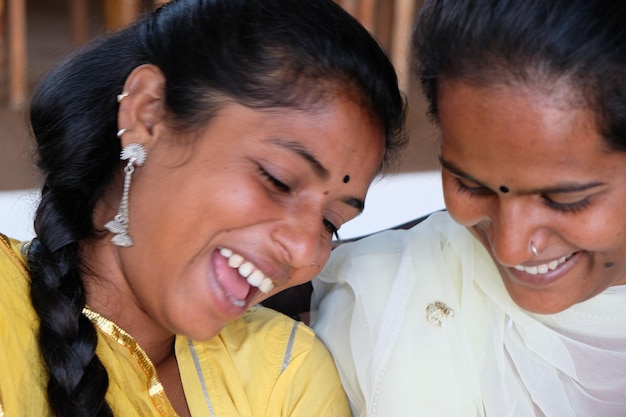 Felici amici femminili indiani che si divertono in un caffè sorridendo e guardando dall'alto in basso qualcosa