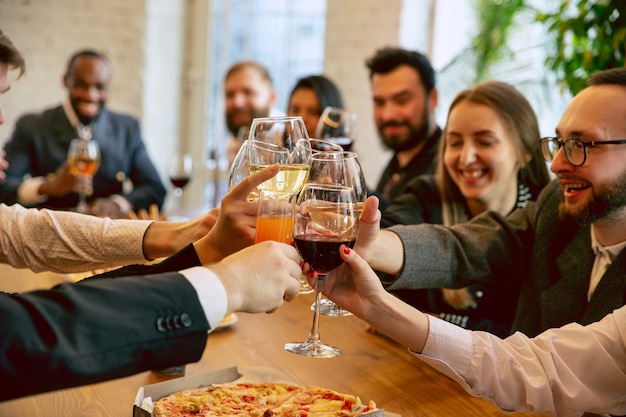 Felici colleghi che festeggiano durante la festa aziendale e l'evento aziendale. Giovani caucasici in abiti da lavoro che applaudono, ridono. Concetto di cultura dell'ufficio, lavoro di squadra, amicizia, vacanze, fine settimana.