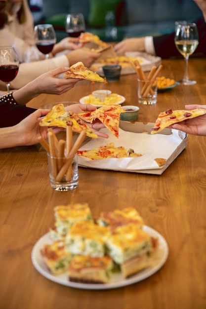 Felici colleghi che festeggiano durante una festa aziendale, un evento aziendale. I giovani caucasici in abiti da lavoro parlano, bevono vino, mangiano spuntini. Concetto di cultura dell'ufficio, lavoro di squadra, amicizia, fine settimana.