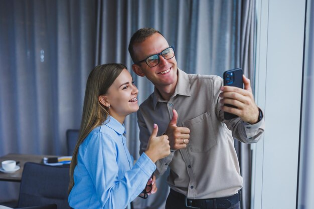 Felici colleghi di lavoro che lavorano insieme in ufficio e usano il telefono I colleghi si fanno un selfie durante una pausa