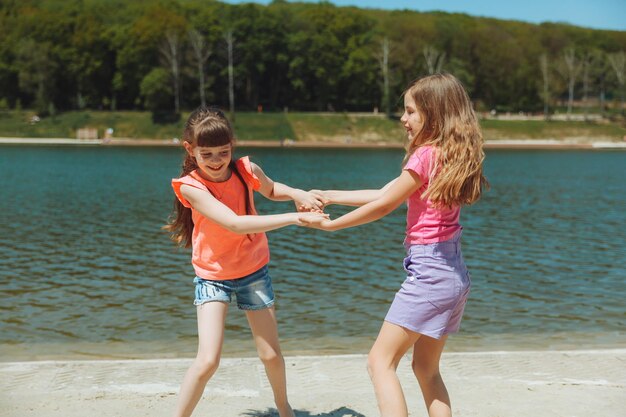 Felici due bambine si divertono e corrono gioiosamente sulla spiaggia saltando sulla sabbia