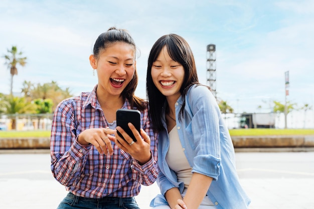 Felici e belle amiche cinesi che si legano all'aperto in città Giocose e graziose amiche asiatiche che si incontrano e si divertono al di fuori di concetti sullo stile di vita e sull'amicizia