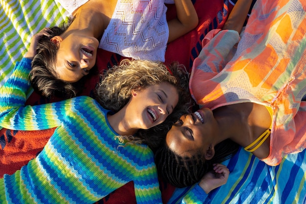 Felici e diverse amiche sdraiate sugli asciugamani e sorridenti in giardino. Stile di vita, amicizia e festa, estate, sole, inalterato.