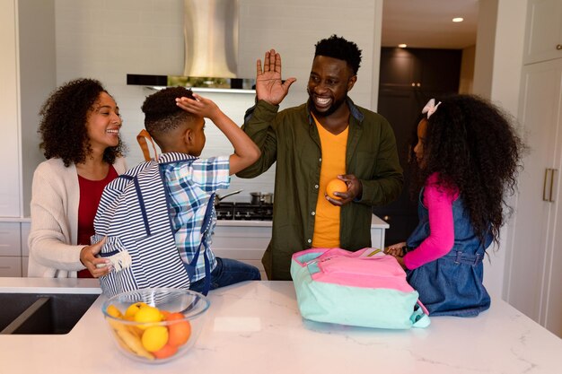 Felici genitori e bambini afroamericani che preparano zaini per la scuola