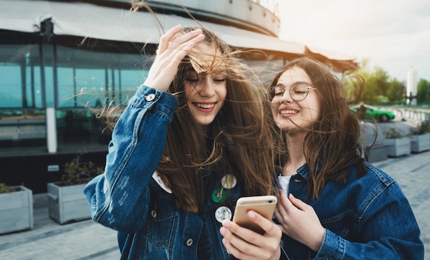 Felici giovani migliori amici che utilizzano i social media sui loro smartphone