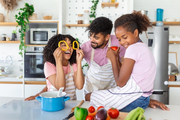 Felici i genitori afroamericani e i loro bambini che si divertono mentre cucinano