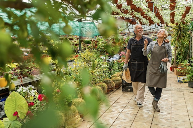 Felici i proprietari di serre che camminano nel vivaio e ammirano i loro fiori