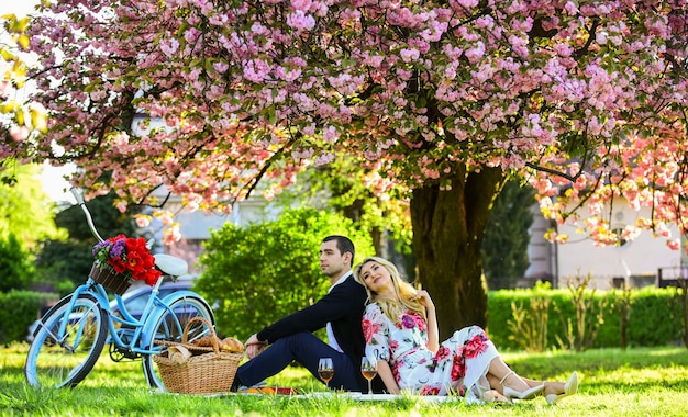 Felici insieme. Fiori simbolo di romanticismo e affetto. Godendo il loro appuntamento perfetto. Coppia rilassante nel parco con la bicicletta. Picnic romantico con vino. Coppia in amore picnic data. Fine settimana di primavera.