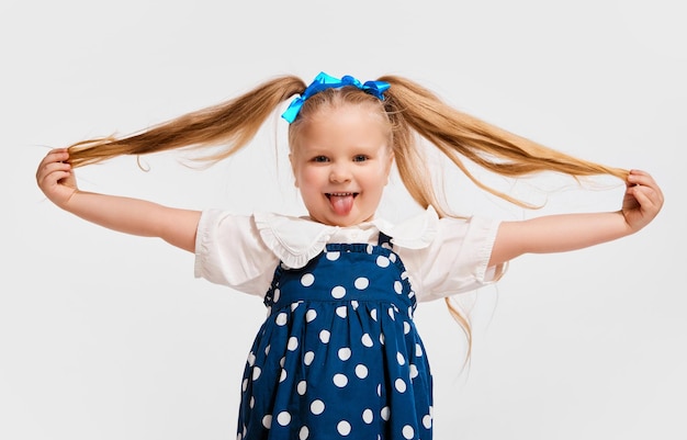 Felicità bella bambina carina in abito stile retrò sorridente in posa contro lo studio grigio