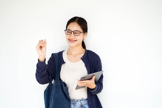 Felicità da vicino allegra giovane studentessa asiatica in abiti casuali che tiene una tavoletta con penna bianca su uno sfondo bianco con gradiente concetto scolastico asiatico