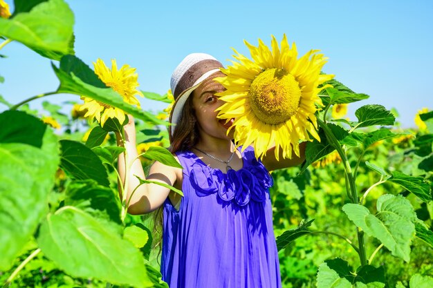 Felicità dell'infanzia ritratto di bambino felice con bel girasole bambino allegro in cappello di paglia tra fiori gialli piccola ragazza in campo di girasole estivo felice giornata dei bambini Pensando all'ecologia