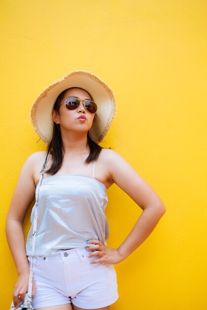 Felicità delle donne asiatiche con tesa e occhiali da sole
