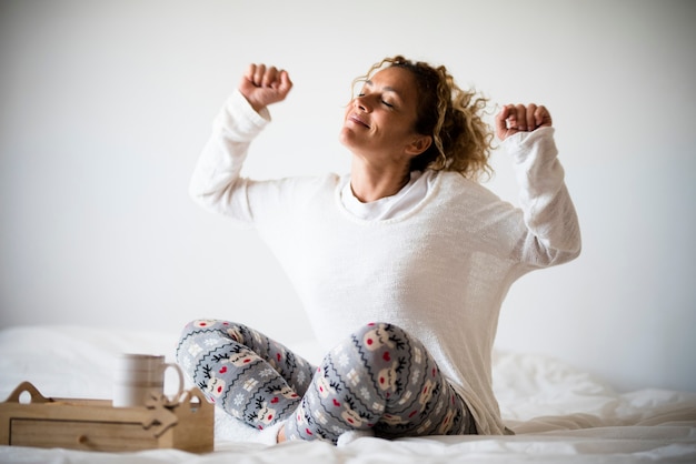 Felicità e buon concetto di vita con una giovane donna adulta felice che si sveglia e si gode la luce del mattino - casa o camera d'albergo - persone che si svegliano e vivono uno stile di vita piacevole