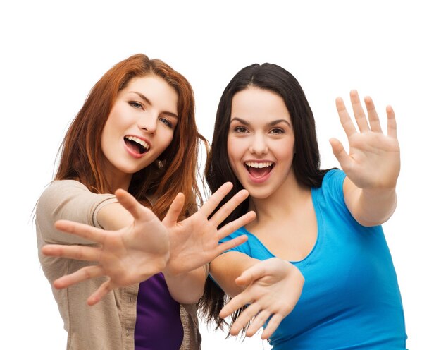 felicità e concetto di persone - due ragazze sorridenti che mostrano i palmi delle mani