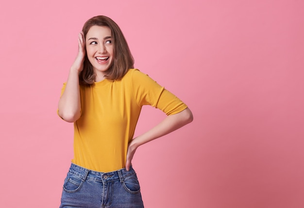 Felicità eccitata della bella donna che indossa maglietta gialla casuale sul rosa.