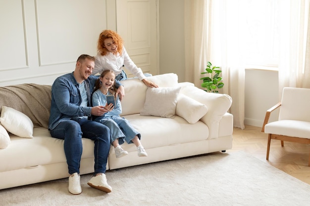 Felicità familiare genitori e figlia eccitati che fanno videochiamate o si fanno selfie sullo smartphone