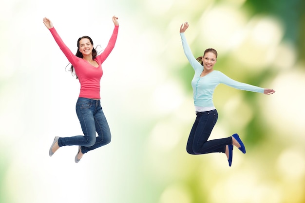 felicità, libertà, ecologia, amicizia e concetto di persone - giovani donne sorridenti che saltano in aria su sfondo verde