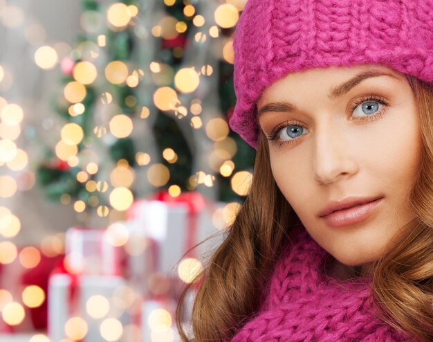 felicità, vacanze invernali e concetto di persone - primo piano di una giovane donna sorridente con cappello rosa e sciarpa sopra l'albero di natale con sfondo di regali