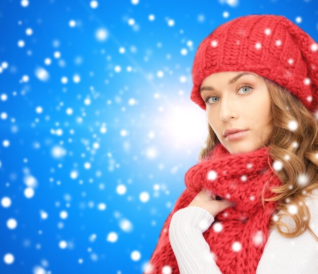 felicità, vacanze invernali, natale e concetto di persone - giovane donna con cappello rosso e sciarpa su sfondo blu innevato