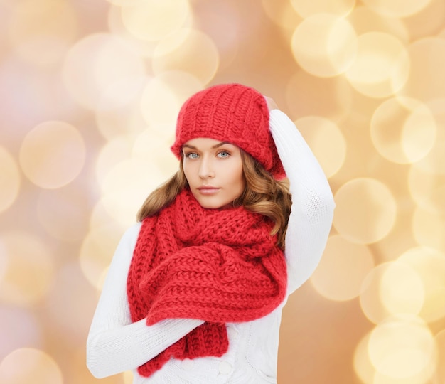felicità, vacanze invernali, natale e concetto di persone - giovane donna con cappello rosso e sciarpa su sfondo di luci beige