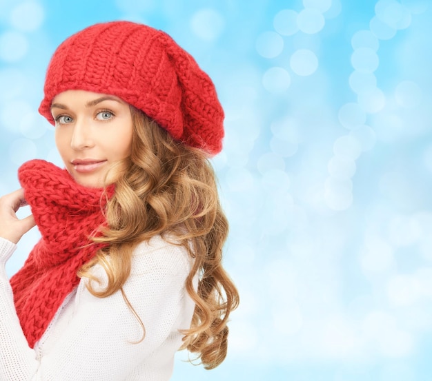 felicità, vacanze invernali, natale e concetto di persone - giovane donna con cappello rosso e sciarpa su sfondo di luci blu