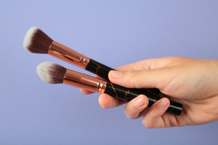Female hand with makeup artist brush on purple background