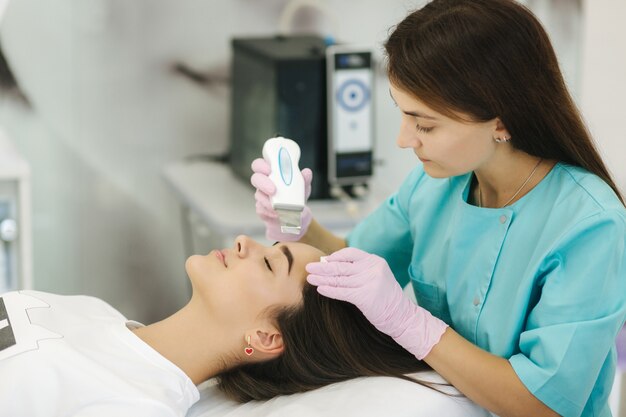 Femmina alla clinica di bellezza cosmetica spa ha cosmetologia hardware facciale Donna che fa le procedure di bellezza