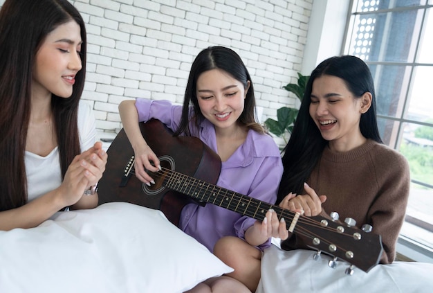 femmina asiatica che suona la chitarra in camera da letto