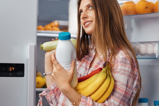 Femmina che cattura alimento da una fine del frigorifero sulla foto