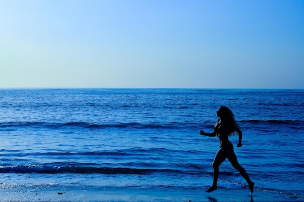 Femmina che corre lungo la spiaggia all'alba