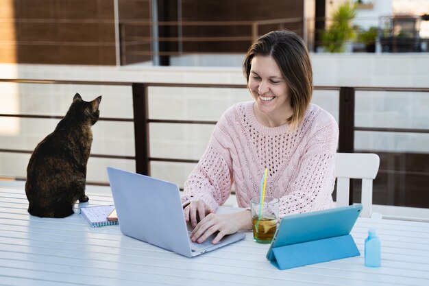 Femmina che lavora da remoto a casa terrazza con il suo animale domestico