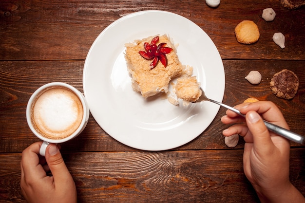 Femmina che mangia caffè dolce della tazza del dessert sulla tavola di legno