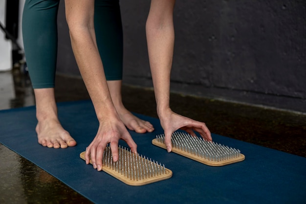 Femmina che tiene in mano la scheda sadhu con chiodi affilati e si prepara per la pratica dello yoga mattutino