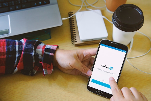 Femmina che tiene smartphone a portata di mano e iniziare a utilizzare l'applicazione LinkedIn